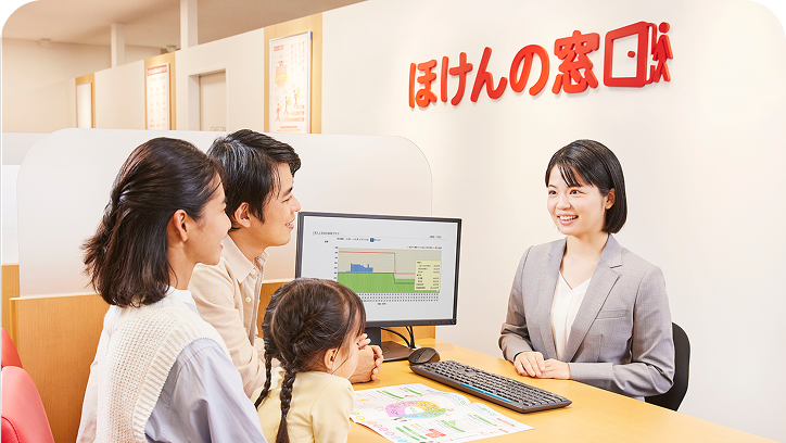 ほけんの窓口のオフィスで、子連れの家族に笑顔で対応する女性スタッフの様子