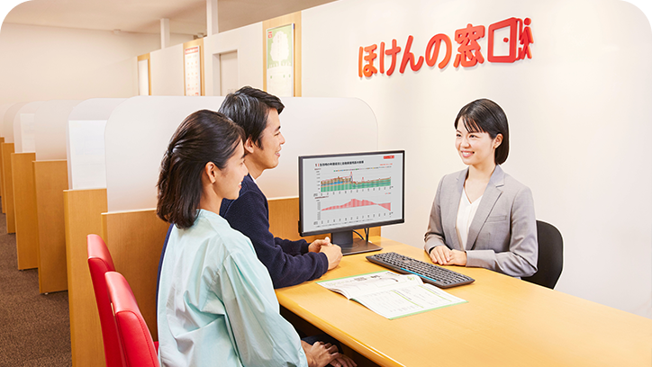 笑顔の女性スタッフがライフプランの円グラフが表示されたモニターを指差して説明している様子